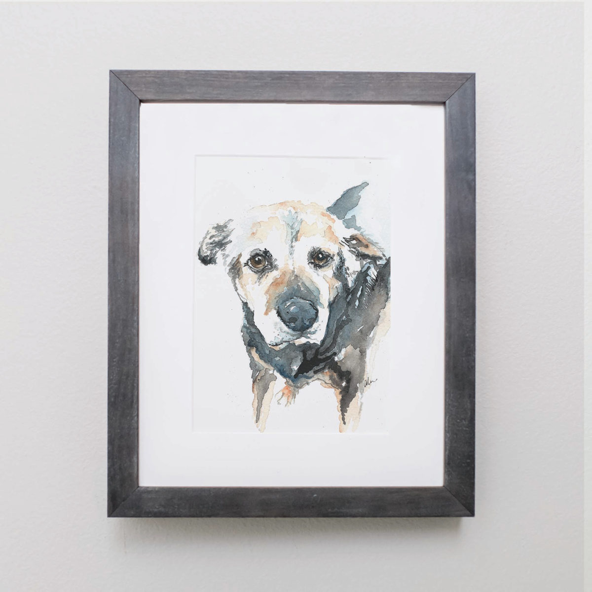 Watercolor of a cream and black dog in a gray frame