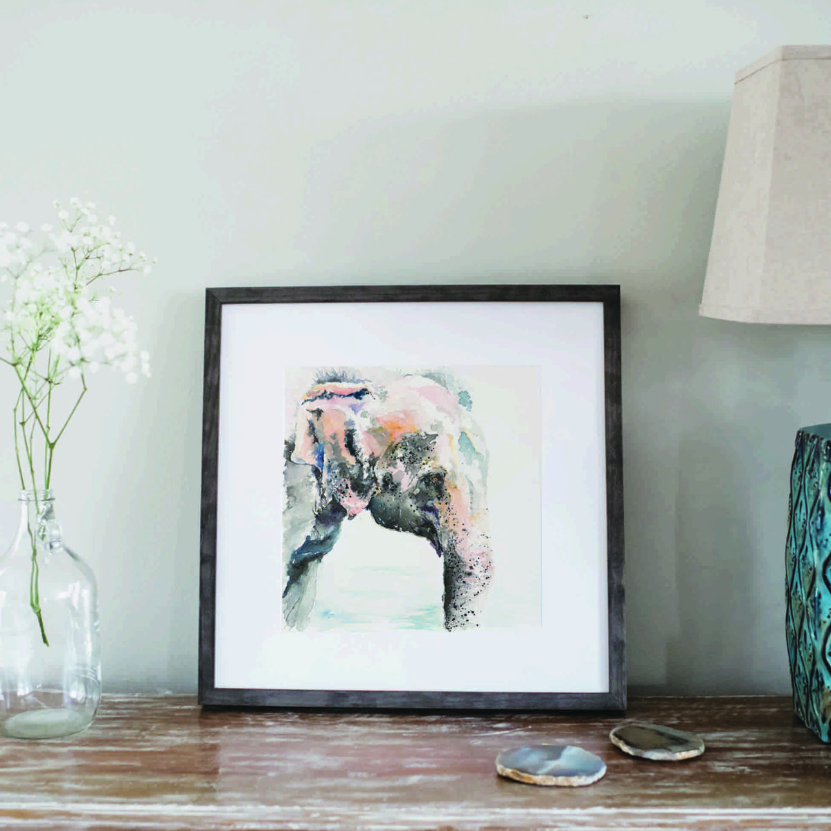 Watercolor of Asian elephant in gray frame next to flowers