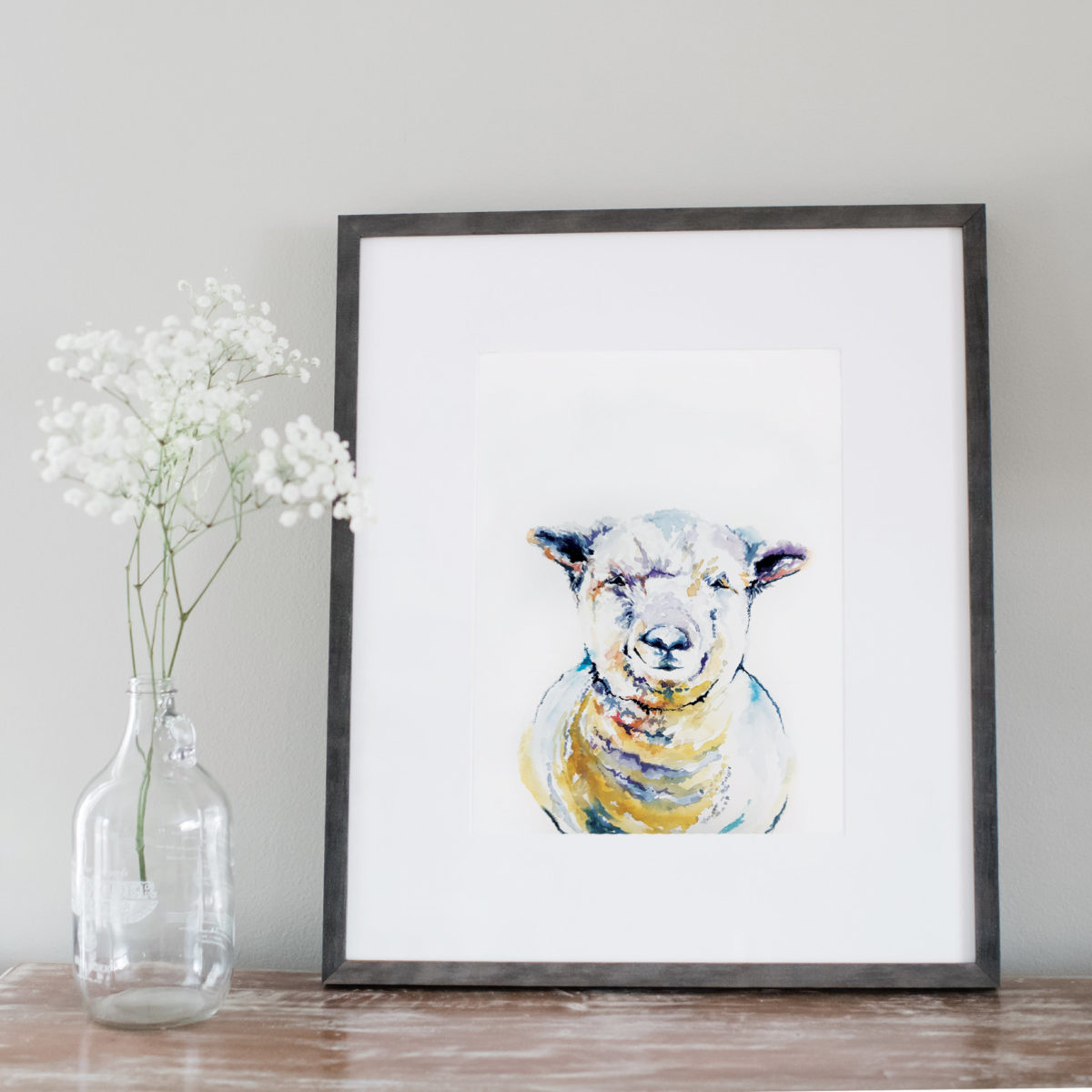 Watercolor of a sheep framed next to flowers
