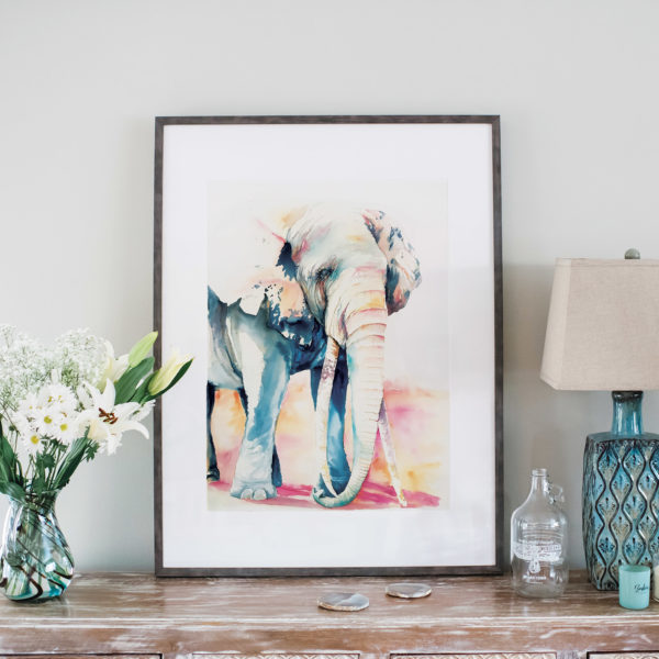 Watercolor of elephant with tusks in frame next to flowers