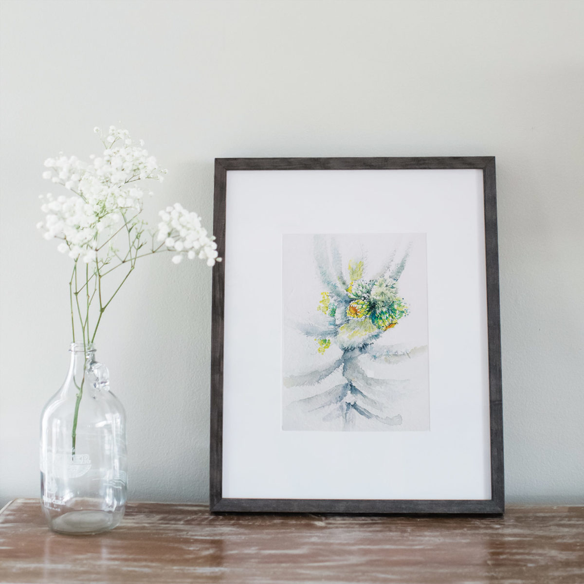 Watercolor of cactus framed next to flowers