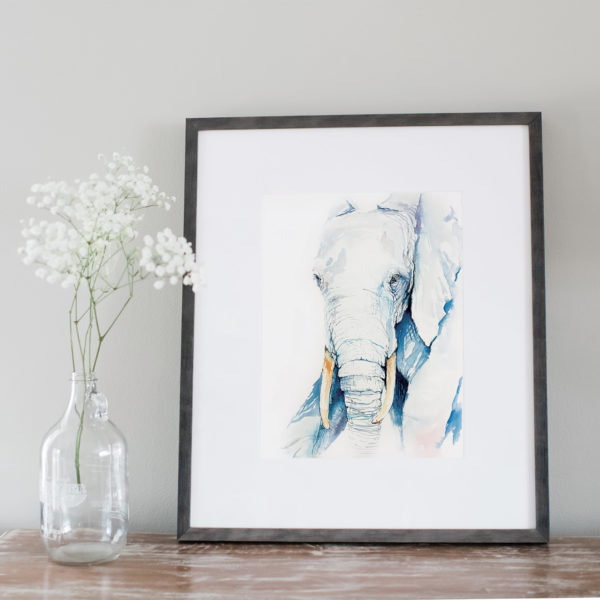 Watercolor of blue elephant framed next to flowers