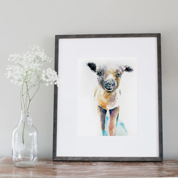 Watercolor of a lamb framed next to flowers