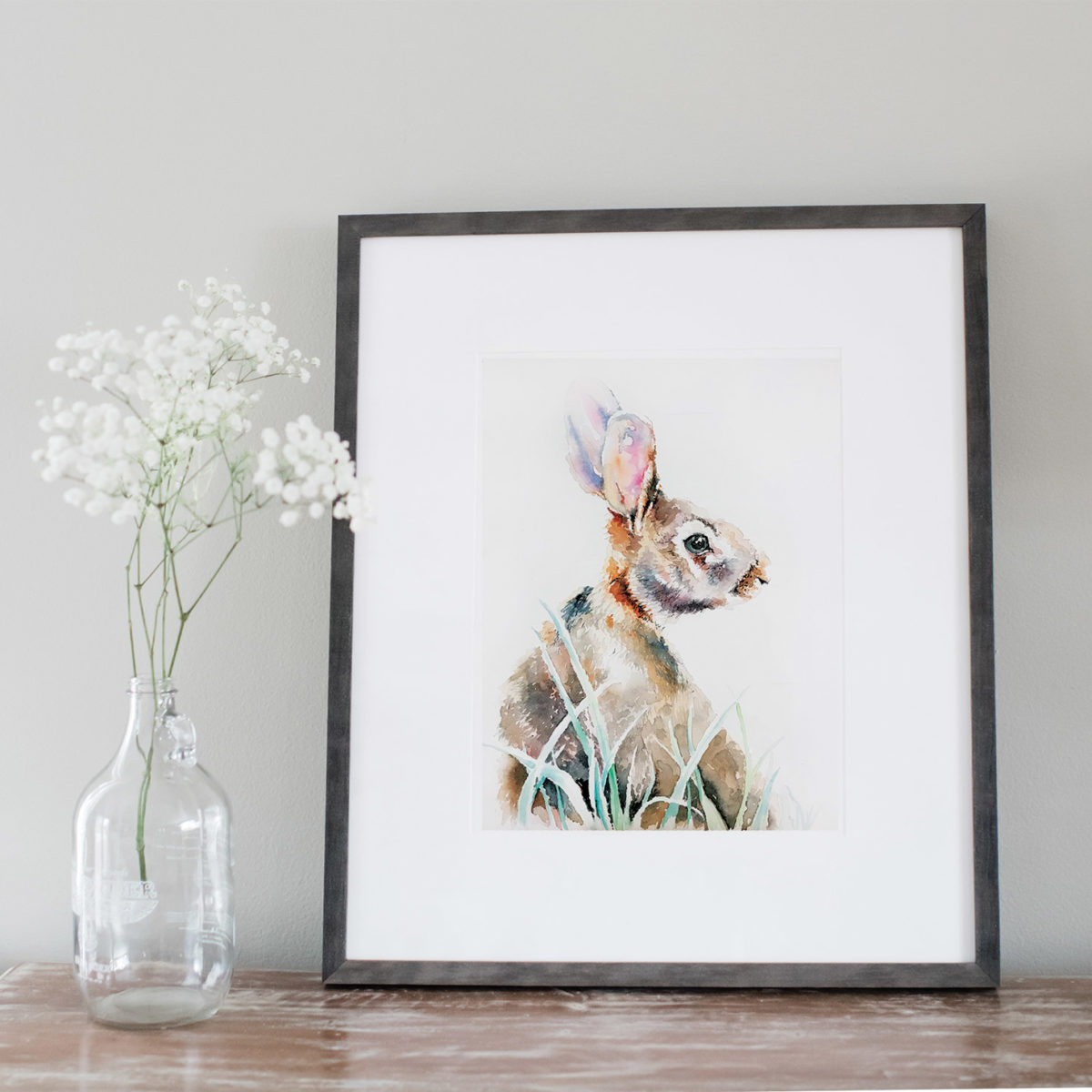 Watercolor of a rabbit framed next to flowers
