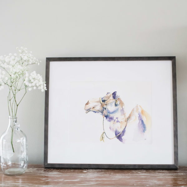Watercolor of a camel in a gray frame next to flowers