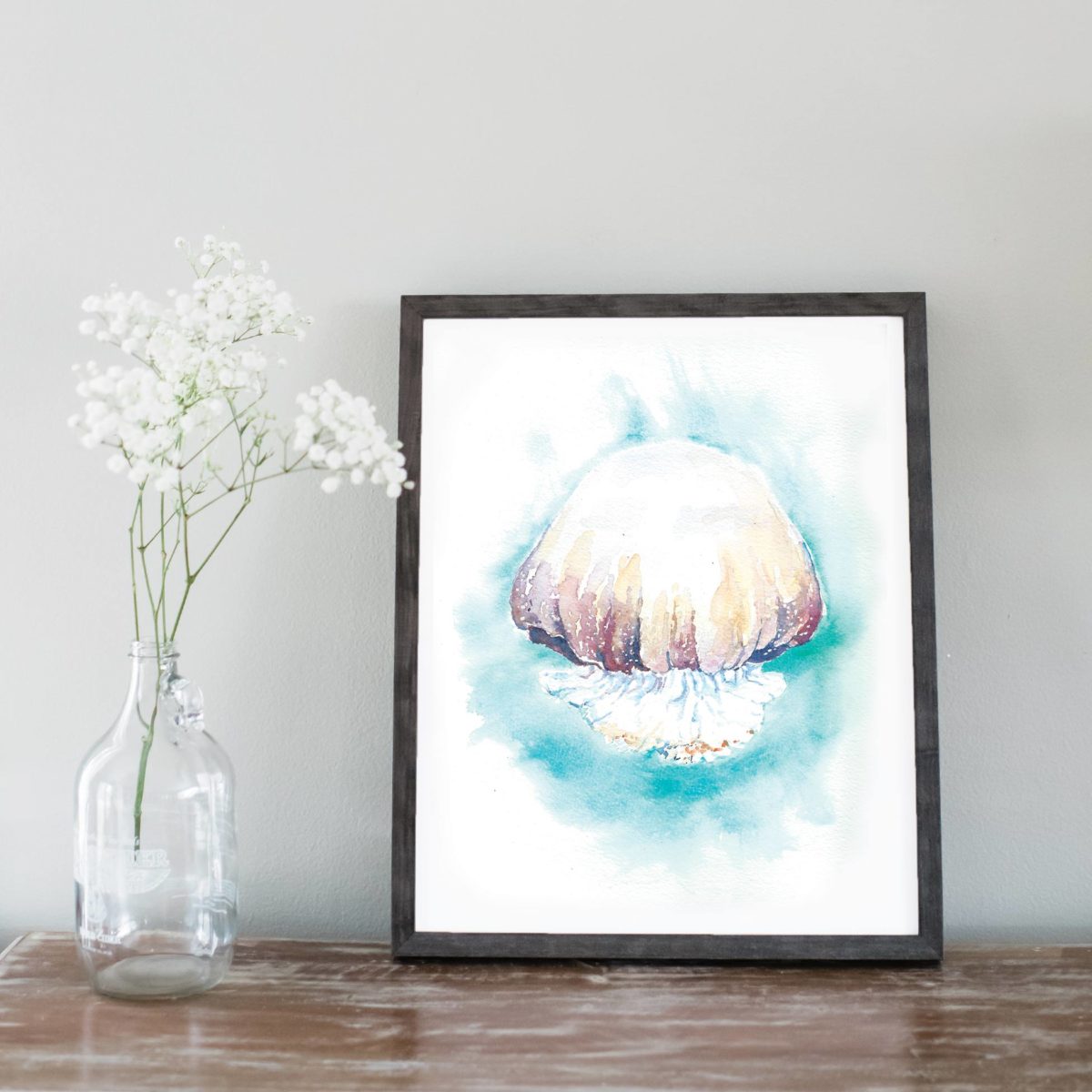 Watercolor of cannon ball jellyfish in gray frame with flowers on left