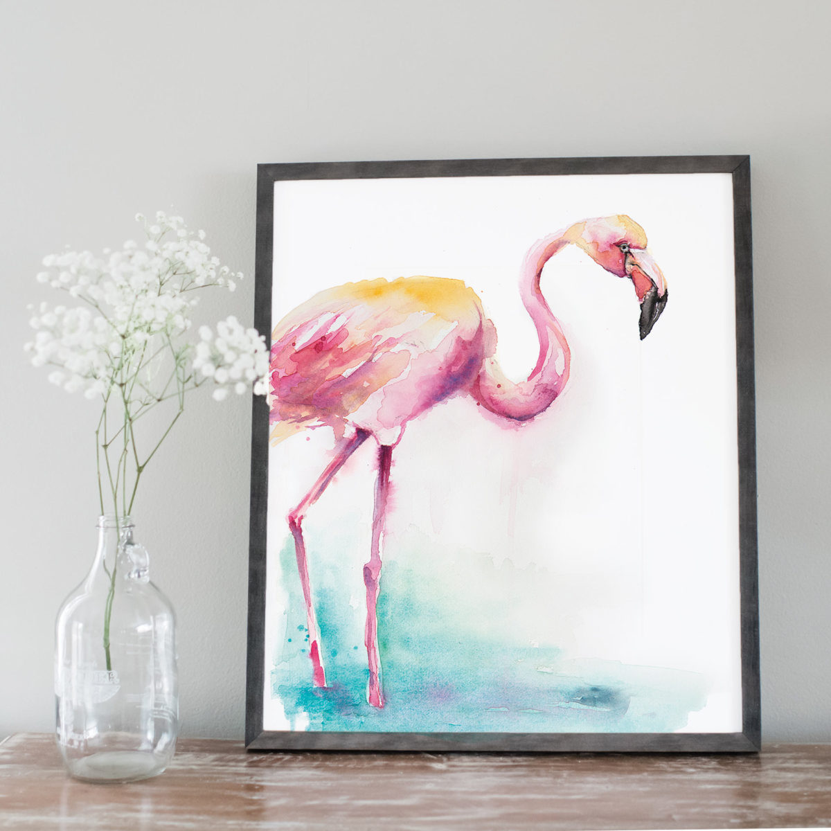 Watercolor of a pink flamingo next to flowers