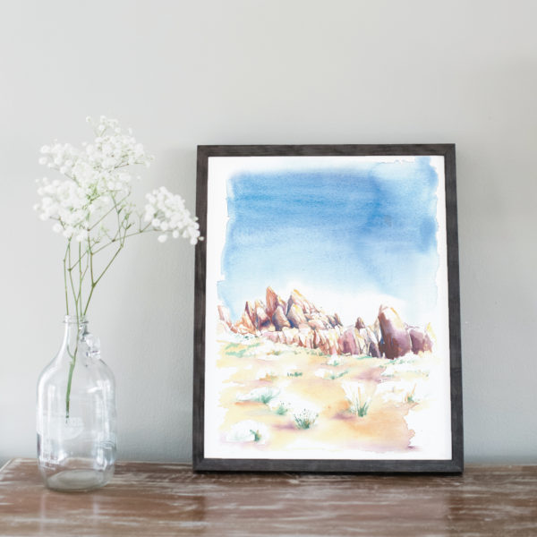 Watercolor of the Alabama Hills in a gray frame next to flowers