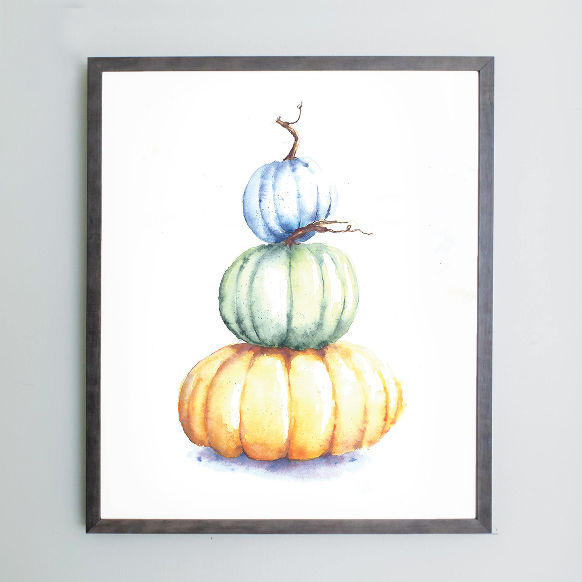 Watercolor of blue, green, and yellow pumpkin in a gray frame